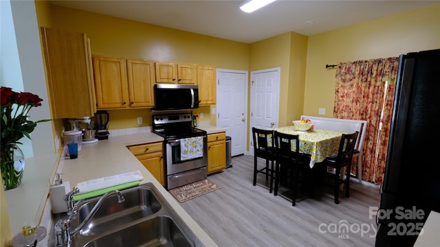 7046 Dorn Cir, Charlotte, NC 28212 - kitchen featuring appliances with stainless steel finishes, a sink, light wood-style floors, and light countertops