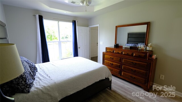7046 Dorn Cir, Charlotte, NC 28212 - bedroom with wood finished floors, a tray ceiling, and baseboards