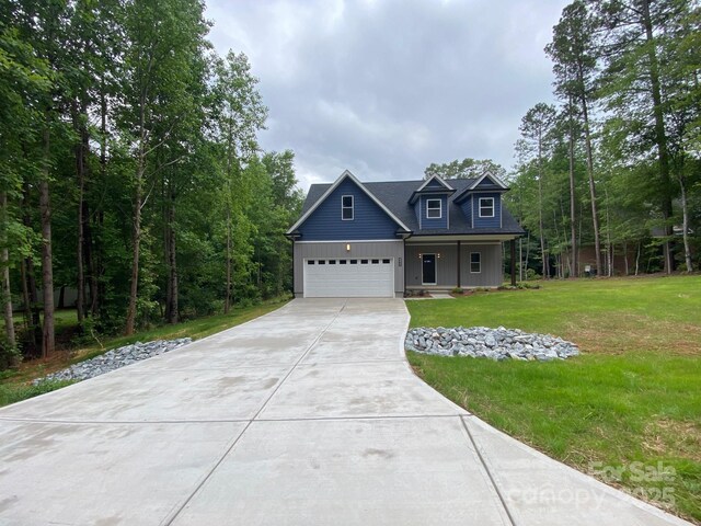 4435 Cornett Dr Unit 30, Iron Station, NC 28080 - view of front facade featuring covered porch, concrete driveway, board and batten siding, a front lawn, and a garage