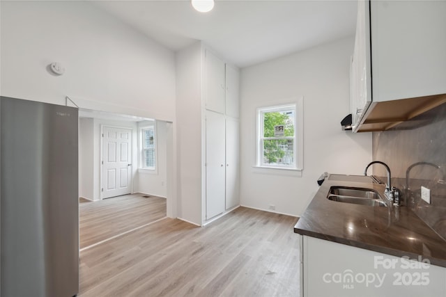 506 N Styers St, Cherryville, NC 28021 - kitchen with a sink, dark countertops, light wood-style floors, freestanding refrigerator, and white cabinets