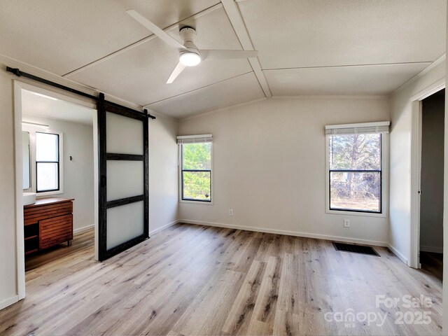 1038 Gold Mine Dr, Catawba, NC 28609 - unfurnished bedroom featuring a barn door, light wood-style flooring, vaulted ceiling, baseboards, and crown molding