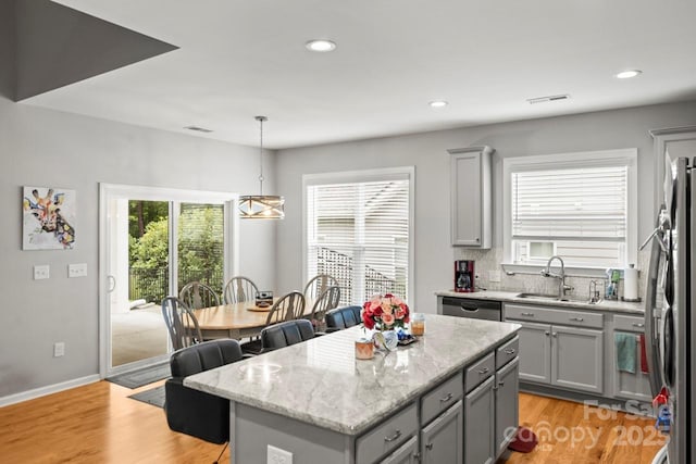 219 Broadleaf Dr, Denver, NC 28037 - kitchen with gray cabinets, a sink, appliances with stainless steel finishes, a center island, and light stone countertops
