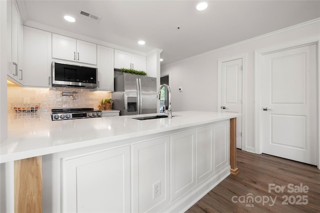 18679 Vineyard Point Ln, Cornelius, NC 28031 - kitchen with stainless steel appliances, a sink, crown molding, dark wood-style flooring, and backsplash