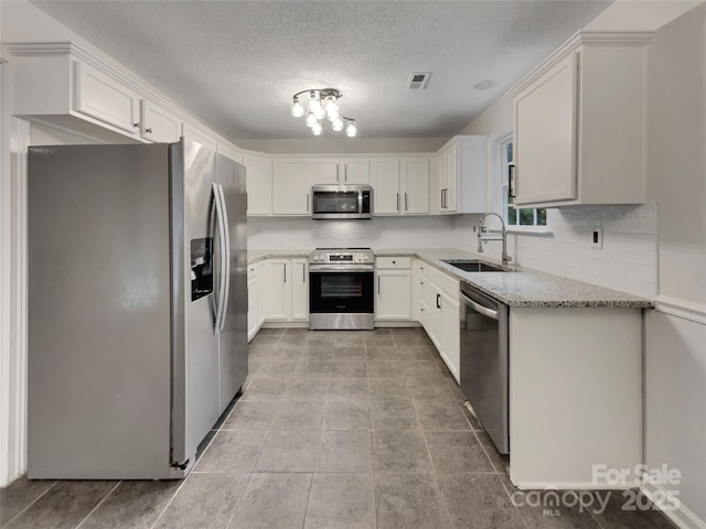 12307 Poplar Forest Dr, Charlotte, NC 28278 - kitchen featuring appliances with stainless steel finishes, a sink, light stone counters, a textured ceiling, and tasteful backsplash