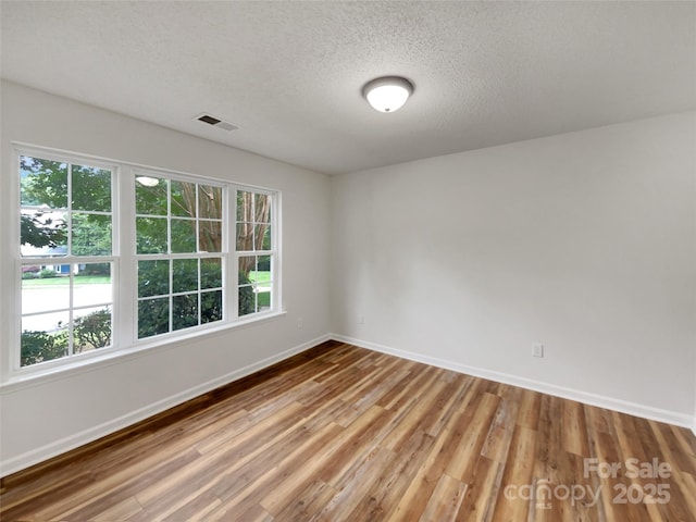 12307 Poplar Forest Dr, Charlotte, NC 28278 - unfurnished room with baseboards, wood finished floors, a textured ceiling, and plenty of natural light