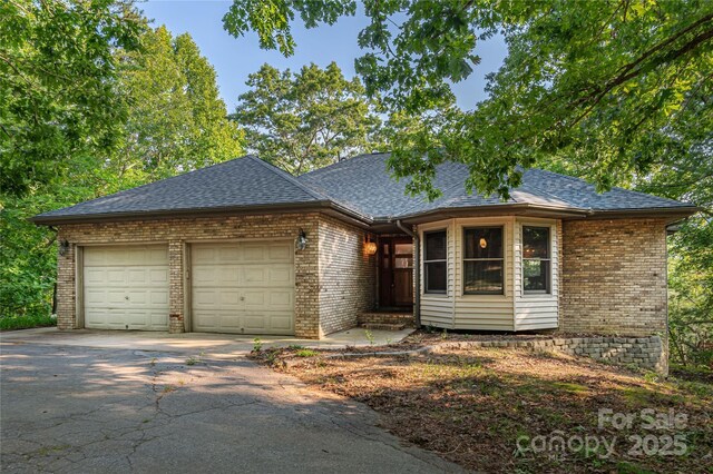 1227 Brush Creek Cir, Fairview, NC 28730 - view of front of house with brick siding, a garage, asphalt driveway, and a shingled roof