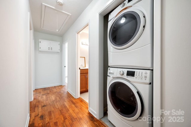 205 Cowan Cove Rd, Asheville, NC 28806 - laundry room with stacked washing machine and dryer, attic access, light wood-type flooring, and baseboards
