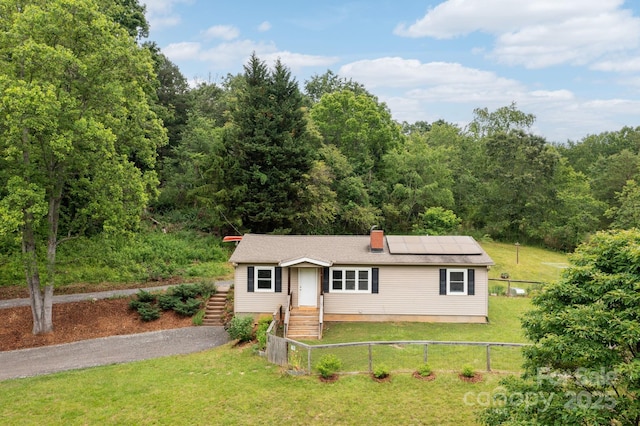 205 Cowan Cove Rd, Asheville, NC 28806 - view of front of house featuring roof mounted solar panels, a chimney, and a wooded view
