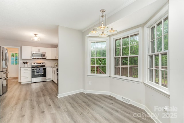 14027 Hackamore Dr, Matthews, NC 28105 - kitchen with stainless steel appliances, white cabinetry, light countertops, light wood-style floors, and decorative light fixtures