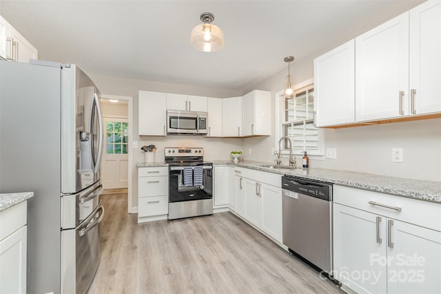 14027 Hackamore Dr, Matthews, NC 28105 - kitchen with appliances with stainless steel finishes, white cabinets, light wood-style flooring, light stone counters, and hanging light fixtures