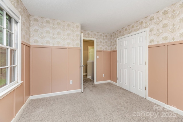 14027 Hackamore Dr, Matthews, NC 28105 - unfurnished bedroom with wallpapered walls, wainscoting, light colored carpet, and a decorative wall