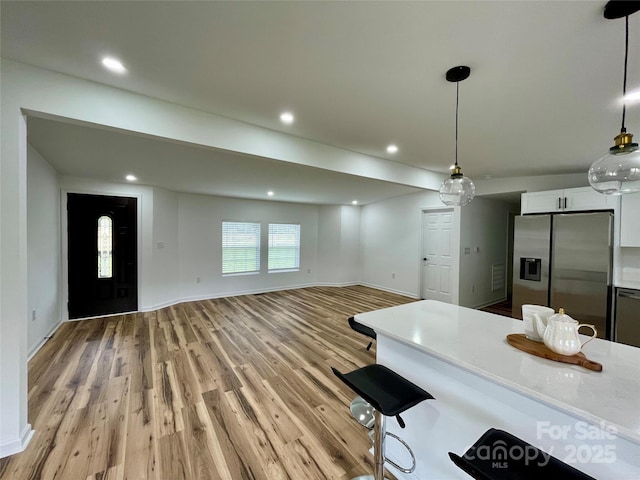 117 Autumn Woods Dr, Kings Mountain, NC 28086 - kitchen featuring stainless steel fridge, white cabinets, light countertops, light wood finished floors, and decorative light fixtures