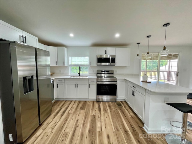 117 Autumn Woods Dr, Kings Mountain, NC 28086 - kitchen featuring stainless steel appliances, a sink, a peninsula, light wood-style floors, and white cabinets
