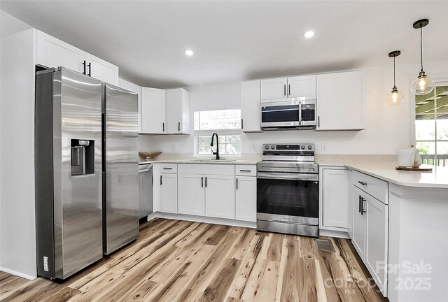 117 Autumn Woods Dr, Kings Mountain, NC 28086 - kitchen with stainless steel appliances, white cabinetry, light countertops, light wood-style flooring, and a peninsula