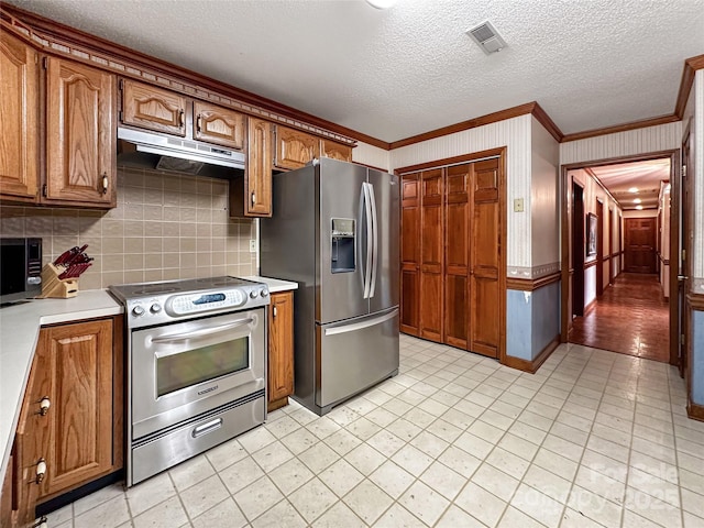 1700 Abbottsford Dr, Kernersville, NC 27284 - kitchen featuring appliances with stainless steel finishes, under cabinet range hood, ornamental molding, brown cabinets, and decorative backsplash