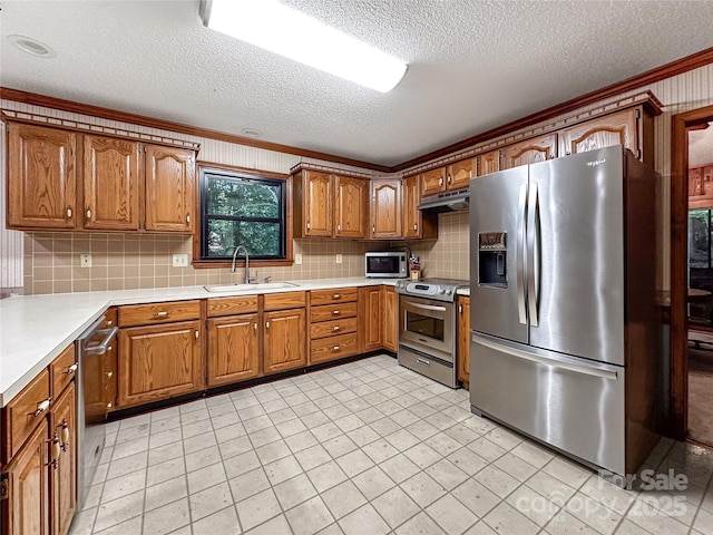 1700 Abbottsford Dr, Kernersville, NC 27284 - kitchen with appliances with stainless steel finishes, a sink, under cabinet range hood, brown cabinetry, and a textured ceiling