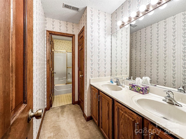 1700 Abbottsford Dr, Kernersville, NC 27284 - bathroom with a textured ceiling, double vanity, wallpapered walls, baseboards, and combined bath / shower with glass door