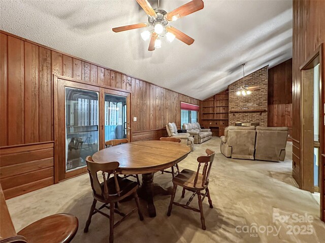 1700 Abbottsford Dr, Kernersville, NC 27284 - dining area with wooden walls, ceiling fan, vaulted ceiling, light colored carpet, and a brick fireplace