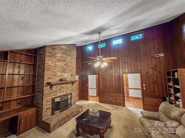 1700 Abbottsford Dr, Kernersville, NC 27284 - carpeted living room with wooden walls, a textured ceiling, a brick fireplace, built in shelves, and a ceiling fan