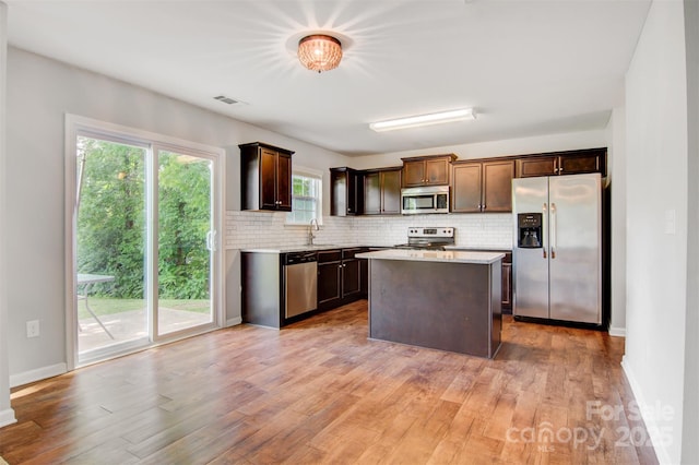 5311 Oakdale Ridge Rd, Charlotte, NC 28216 - kitchen with appliances with stainless steel finishes, decorative backsplash, light wood-style flooring, dark brown cabinets, and a kitchen island