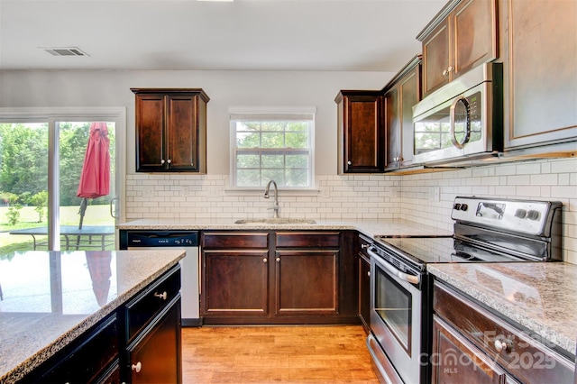 5311 Oakdale Ridge Rd, Charlotte, NC 28216 - kitchen featuring appliances with stainless steel finishes, light stone countertops, light wood-style floors, a sink, and decorative backsplash