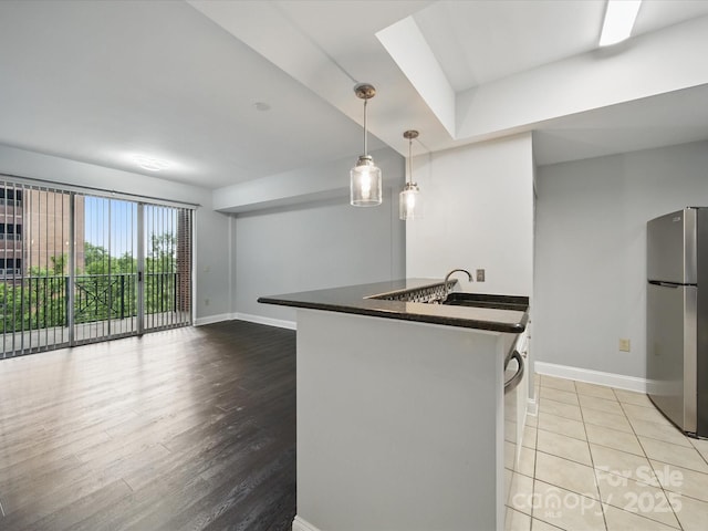 300 W 5th St Unit 339, Charlotte, NC 28202 - kitchen with freestanding refrigerator, dark countertops, a sink, baseboards, and a peninsula