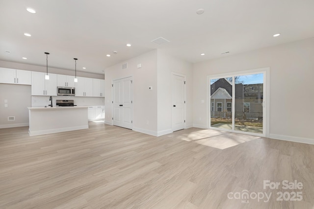 6327 Carver Blvd, Charlotte, NC 28269 - unfurnished living room with light wood-style floors, baseboards, recessed lighting, and a sink