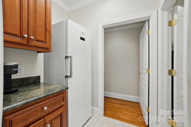 102 Rosewood Ln, Locust, NC 28097 - kitchen with freestanding refrigerator, crown molding, baseboards, light tile patterned flooring, and brown cabinets
