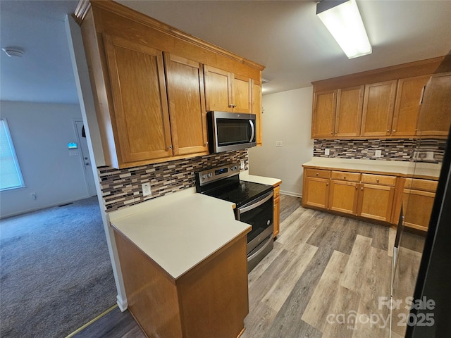 606 N St, Belmont, NC 28012 - kitchen with stainless steel appliances, decorative backsplash, light countertops, light wood-style flooring, and brown cabinets