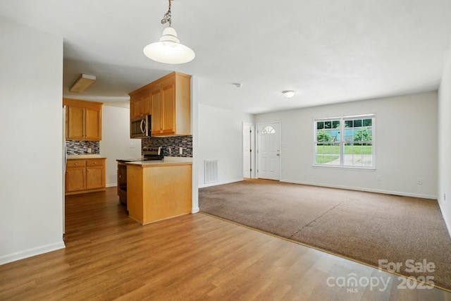 606 N St, Belmont, NC 28012 - kitchen featuring stainless steel appliances, open floor plan, backsplash, hanging light fixtures, and wood finished floors