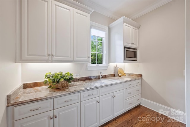 3032 Kings Manor Dr, Matthews, NC 28104 - kitchen with stainless steel microwave, white cabinets, crown molding, light stone counters, and dark wood-type flooring