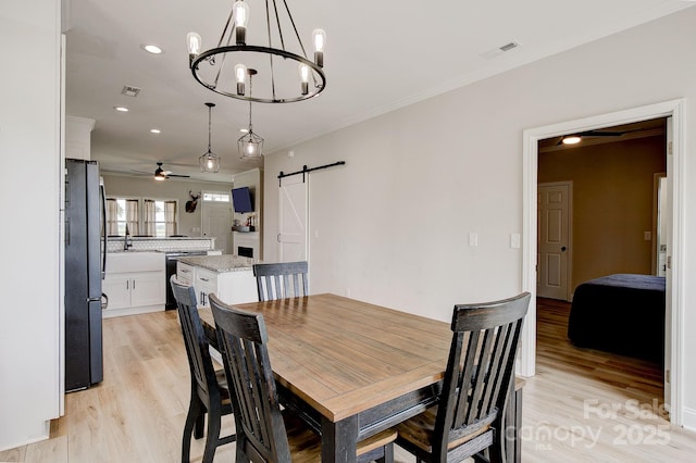 1202 Neds Creek Rd, Kershaw, SC 29067 - dining space with a barn door, ceiling fan, a chandelier, light wood finished floors, and ornamental molding
