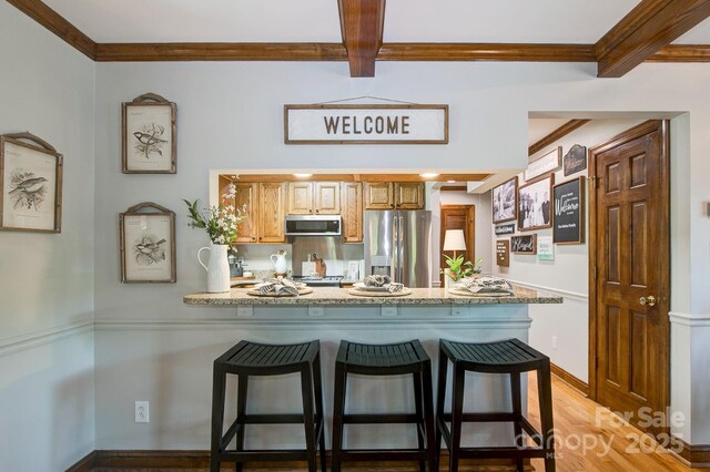 325 Chapman St, Chesterfield, SC 29709 - kitchen featuring appliances with stainless steel finishes, a peninsula, ornamental molding, a breakfast bar area, and light wood-style flooring