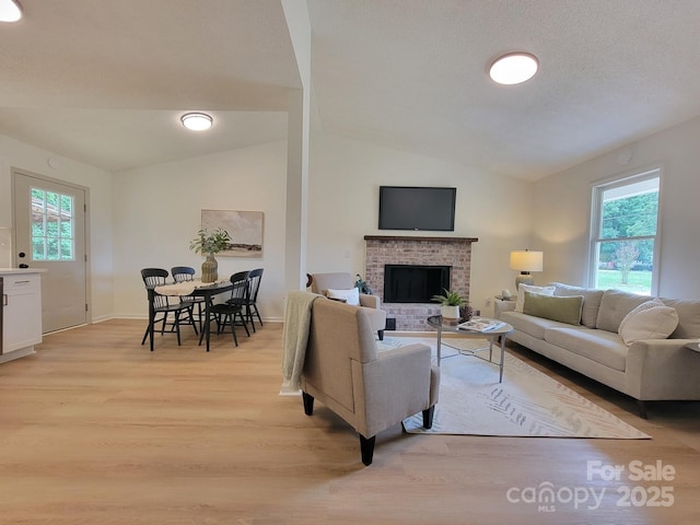2070 Stirewalt Rd, China Grove, NC 28023 - living area featuring light wood-style flooring, vaulted ceiling, plenty of natural light, a fireplace, and baseboards