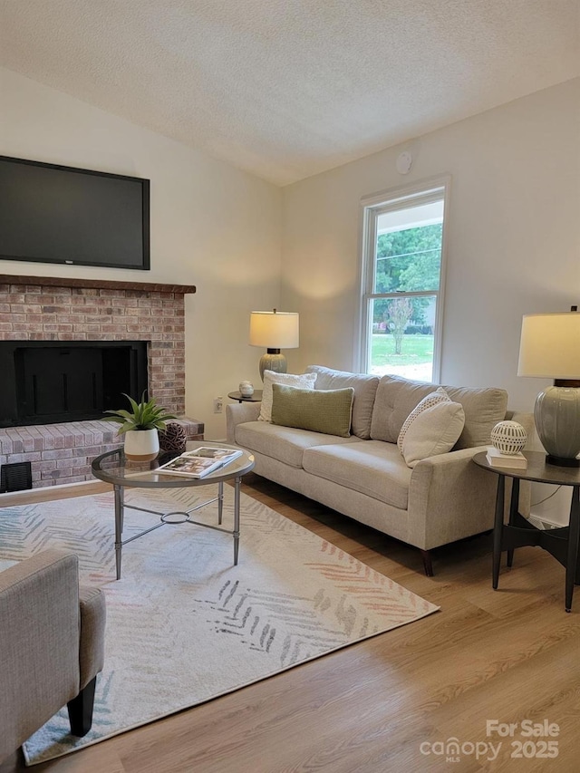 2070 Stirewalt Rd, China Grove, NC 28023 - living area featuring wood finished floors, vaulted ceiling, a textured ceiling, and a brick fireplace