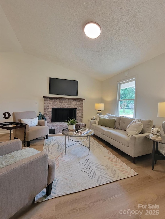 2070 Stirewalt Rd, China Grove, NC 28023 - living room with wood finished floors, vaulted ceiling, a brick fireplace, and a textured ceiling