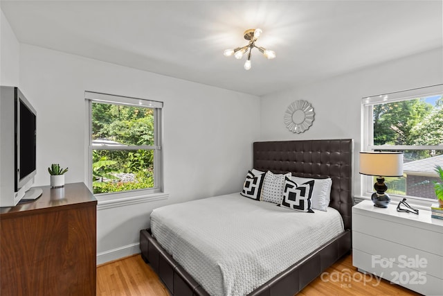 2424 Cumberland Ave, Charlotte, NC 28203 - bedroom featuring multiple windows, a chandelier, and light wood-style floors
