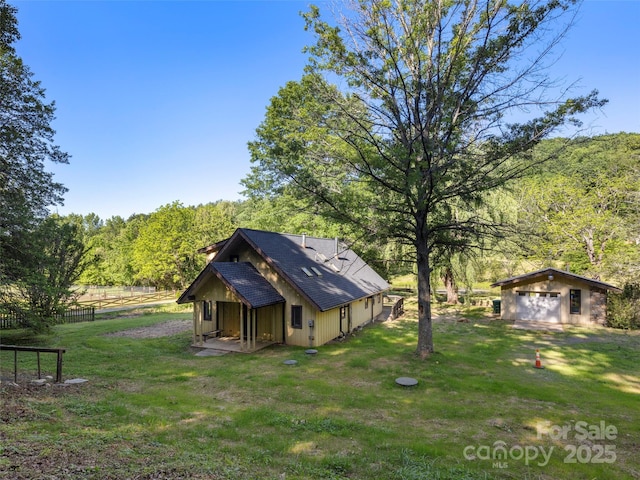 272 Pinners Cove Rd, Asheville, NC 28803 - rear view of house with a detached garage, an outbuilding, a forest view, and roof with shingles