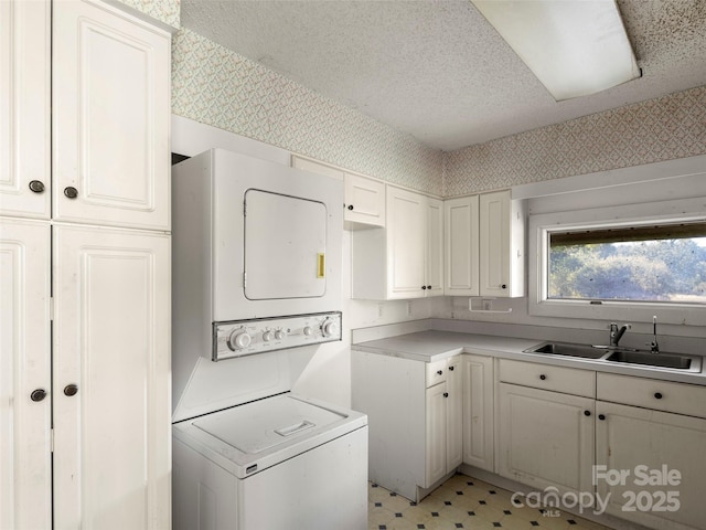 272 Pinners Cove Rd, Asheville, NC 28803 - washroom featuring stacked washer and clothes dryer, a textured ceiling, light floors, wallpapered walls, and cabinet space