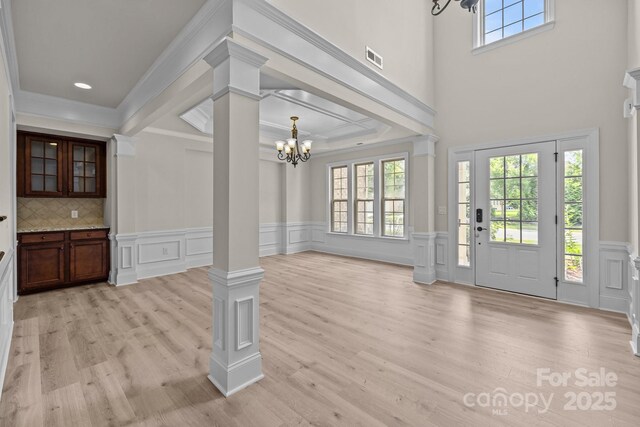 10508 Kristens Mare Dr, Charlotte, NC 28277 - foyer with ornate columns, a chandelier, light wood-style flooring, a decorative wall, and crown molding