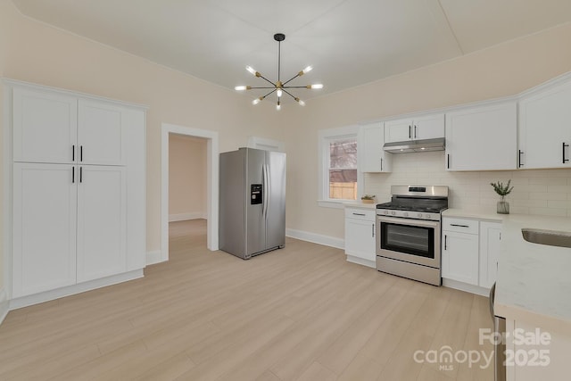 1003 S Ridge Ave, Kannapolis, NC 28083 - kitchen featuring appliances with stainless steel finishes, under cabinet range hood, light countertops, a chandelier, and decorative backsplash