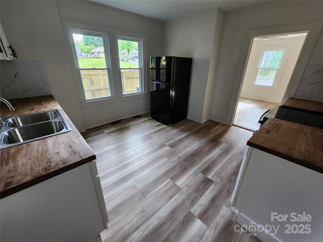 1434 N Hamilton St, High Point, NC 27262 - kitchen featuring freestanding refrigerator, a sink, plenty of natural light, and white cabinetry
