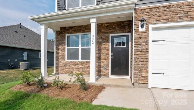 50 Lance Forest Rd, Fletcher, NC 28732 - view of exterior entry with stone siding, central air condition unit, a porch, and a garage