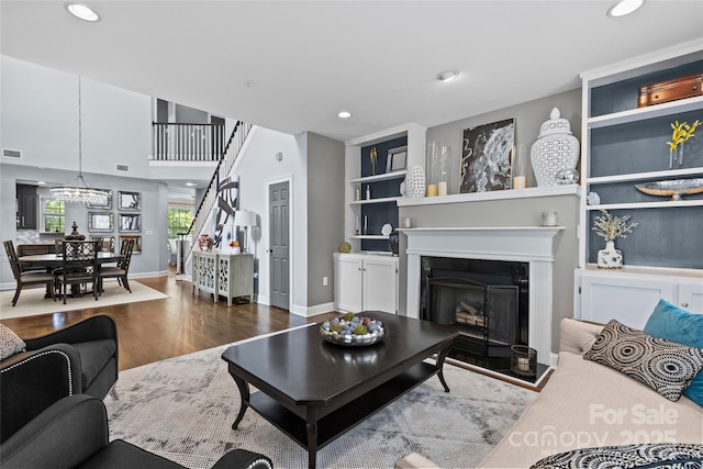 224 Wendover Heights Cir, Charlotte, NC 28211 - living room featuring wood finished floors, recessed lighting, a fireplace with raised hearth, stairway, and built in features