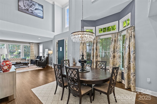 224 Wendover Heights Cir, Charlotte, NC 28211 - dining area featuring a chandelier, baseboards, ornamental molding, wood finished floors, and a towering ceiling