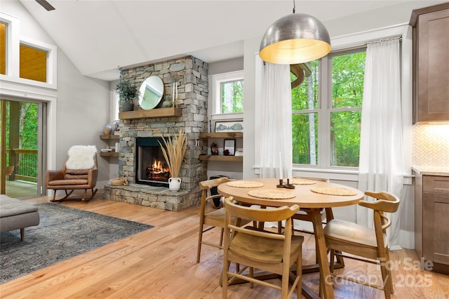 68 Huckleberry Ridge Ln, Zirconia, NC 28790 - dining room featuring a stone fireplace, plenty of natural light, light wood-style floors, and vaulted ceiling
