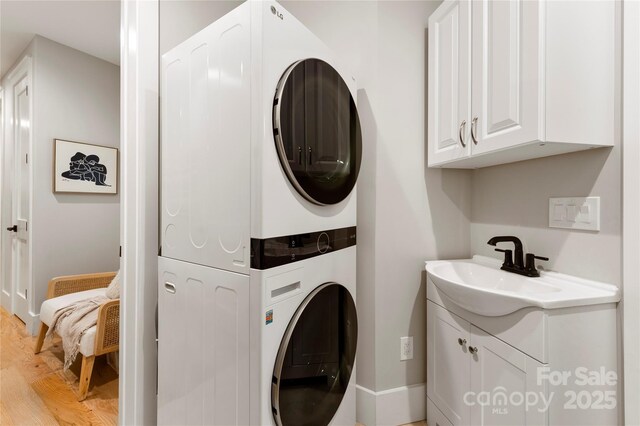 68 Huckleberry Ridge Ln, Zirconia, NC 28790 - laundry area featuring stacked washer / drying machine, cabinet space, light wood finished floors, and baseboards
