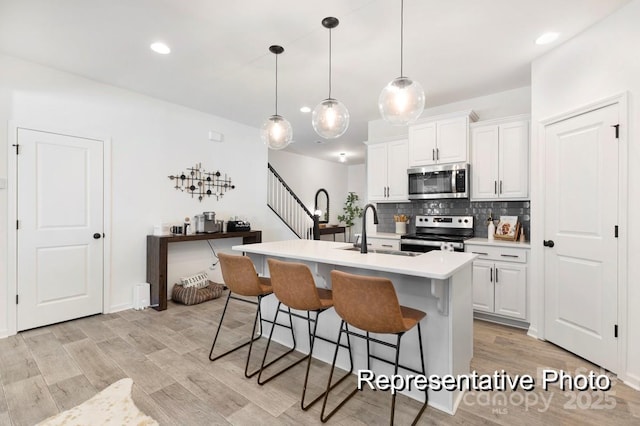 11335 Magpie Ct Unit 8, Charlotte, NC 28215 - kitchen with stainless steel appliances, a sink, a kitchen bar, an island with sink, and light countertops