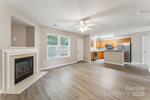13413 Golden Apple Ct, Charlotte, NC 28215 - unfurnished living room featuring light wood finished floors, ceiling fan, a fireplace, and baseboards