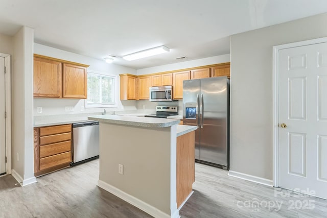 13413 Golden Apple Ct, Charlotte, NC 28215 - kitchen with appliances with stainless steel finishes, light wood-style floors, light countertops, a kitchen island, and baseboards